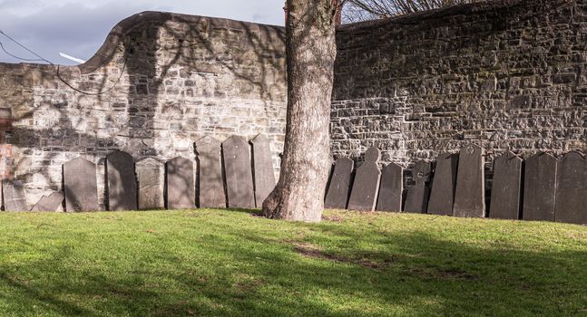 Dublin, Ireland - February 13, 2019: Tombstones laid against a wall in the cemetery at Arbor Hill next to the Church of the Sacred Heart on a winter day