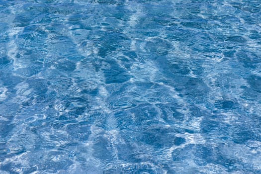 Water surface with bright sun light reflections, sea water background. Water surface with bright sun light reflections. Background of transparent sea water. Blue ripped sea water background.