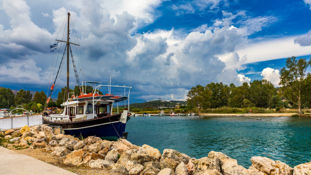 Georgioupoli is a resort village and former municipality in the Chania regional unit, Crete, Greece. Fishing boat in harbour Georgioupolis. Sea, ship and sky with clouds. River Almyros.