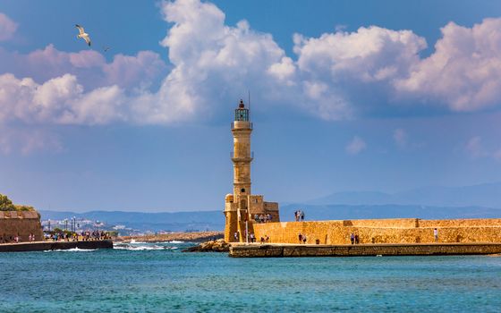 Venetian harbour and lighthouse in old harbour of Chania with seagulls flying over, Crete, Greece. Old venetian lighthouse in Chania, Greece. Lighthouse of the old Venetian port in Chania, Greece.