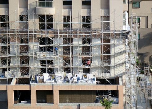 KAOHSIUNG, TAIWAN -- APRIL 18, 2015: Construction workers are working on the facade of a new apartment building in the city.
