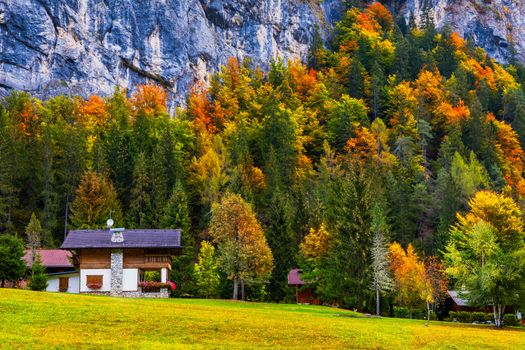 Autumn in the famous Dolomites mountains, Italy, Europe. Dramatic cliffs surround the village with the the iconic mountains and autumn forest. Colorful autumn landscape in mountain village. 