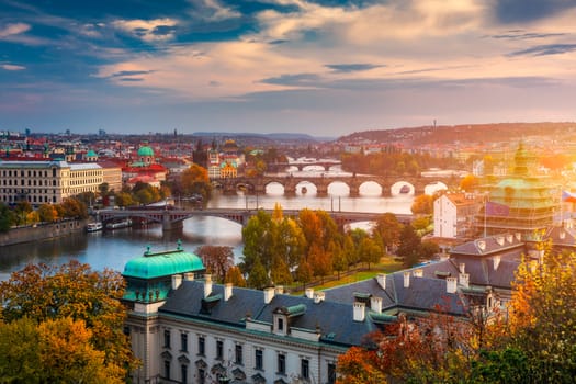 Autumn view to Charles bridge on Vltava river in Prague, Czech Republic. Autumn view to Charles Bridge, Prague old town and Vltava river from Letna park (Letenske sady) at sunset with colorful sky.
