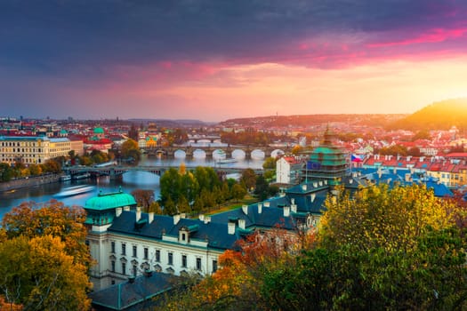 Autumn view to Charles bridge on Vltava river in Prague, Czech Republic. Autumn view to Charles Bridge, Prague old town and Vltava river from Letna park (Letenske sady) at sunset with colorful sky.