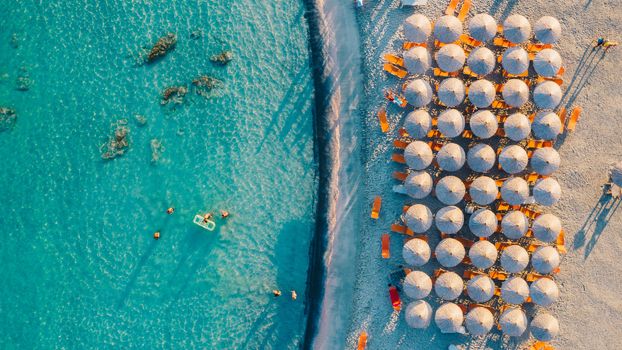 Top down aerial view of amazing beach with umbrellas and turquoise sea at sunset. Mediterranean sea, Crete, Greece.
