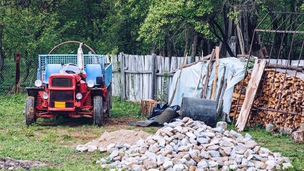 Rural scene of a backyard with tractor and wood pile
