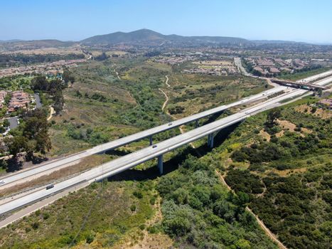 Aerial view of road highway bridge, viaduct supports in the valley among the green hills, transport infrastructure. California, USA 
