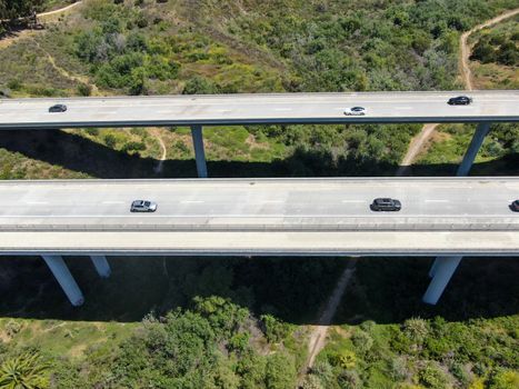 Aerial view of road highway bridge, viaduct supports in the valley among the green hills, transport infrastructure. California, USA 