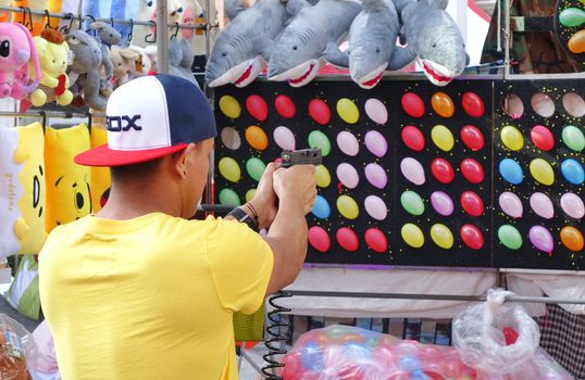 KAOHSIUNG, TAIWAN -- FEBRUARY 6, 2019: A young man uses a pistol to shoot at small balloons at a Chinese New Year Market.

