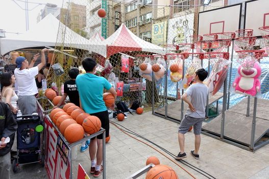 KAOHSIUNG, TAIWAN -- FEBRUARY 6, 2019: People try to score basketball hits in a skill game at a Chinese New Year Market.
