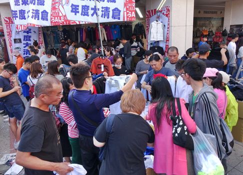 KAOHSIUNG, TAIWAN -- FEBRUARY 6, 2019: People snap up cheap shirts and clothing that is for sale at an outdoor market.
