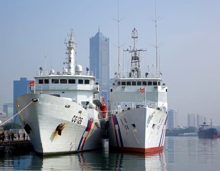 KAOHSIUNG, TAIWAN -- JANUARY 1, 2015: Two large coastguard vessels are anchored in Kaohsiung Port. In the background is 85 story Tuntex Tower.
