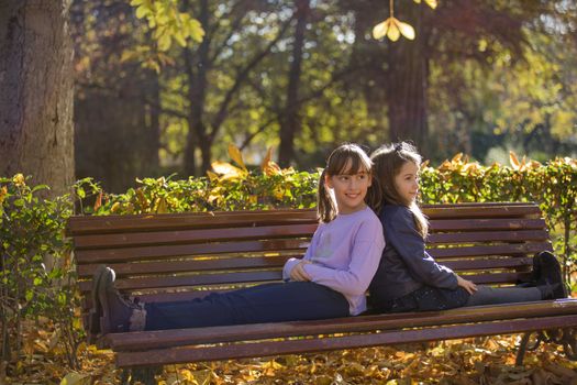 Two girlfriends having fun in a public park in the fall.