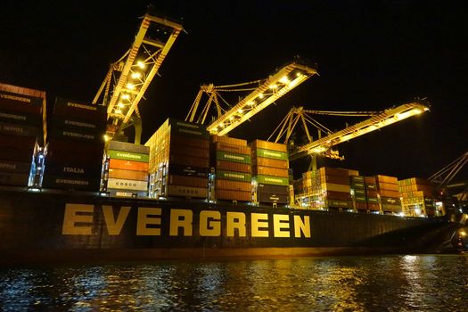 KAOHSIUNG, TAIWAN -- JUNE 2, 2019: Containers are being loaded onto ships in Kaohsiung Port at dusk