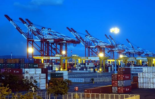 KAOHSIUNG, TAIWAN -- JUNE 2, 2019: Containers are being loaded in Kaohsiung Port at dusk
