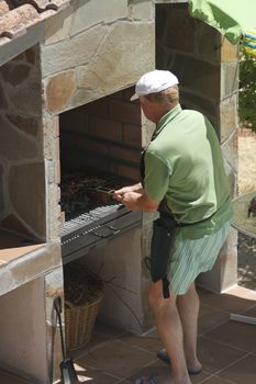 Senior man doing barbecue outdoors at beauty barbecue grill.