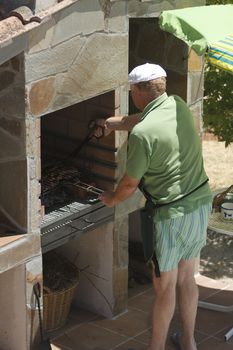 Senior man doing barbecue outdoors at beauty barbecue grill.