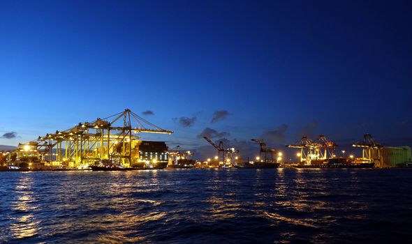 KAOHSIUNG, TAIWAN -- JUNE 2, 2019: Containers are being loaded onto ships in Kaohsiung Port at dusk