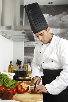 Chef chopping red pepper on cutting board.