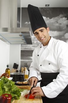 Chef chopping tomatoes on cutting board.