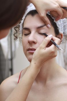 Young woman having make-up applied by a beautician.