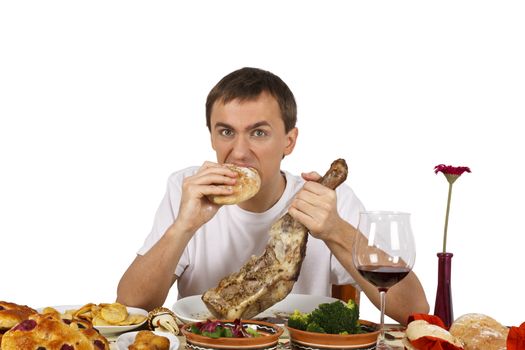 Young man biting bread while he holds a leg of lamb. Isolated of white background.