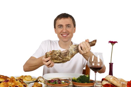 Young man showing a leg of lamb while he has his mouth full of it. Isolated of white background.