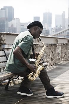 Guy playing a saxophone in Brooklyn bridge. Filters added to get a dramatic look.