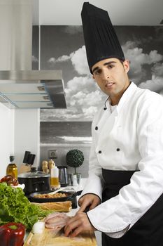 Chef chopping chicken breasts on cutting board.