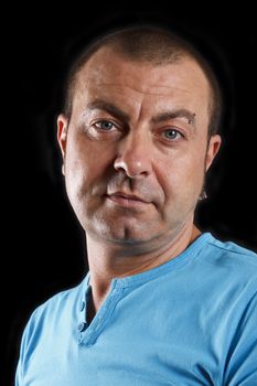 Portrait of handsome man with a blue t-shirt. Over black.