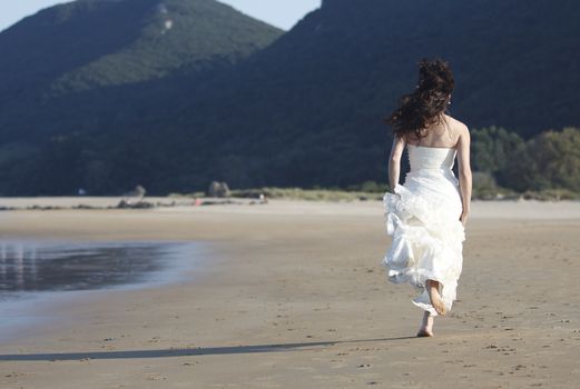 Bride running in the beach.