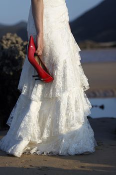 Bride holding red shoes.