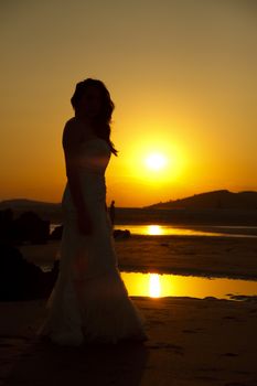 Bride contemplating beach at sunset. Low light