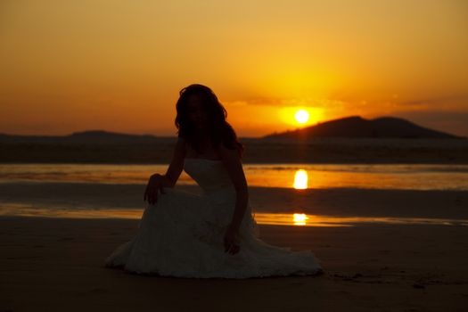 Bride contemplating beach at sunset. Low light