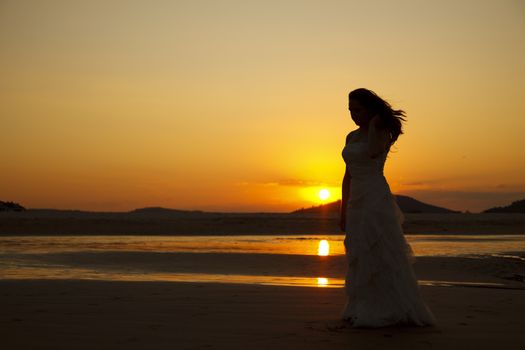 Bride contemplating beach at sunset. Low light