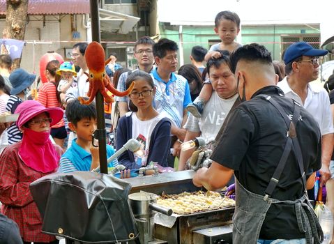 KAOHSIUNG, TAIWAN -- JULY 14, 2018: An outdoor vendor cooks Japanese Takoyaki squid balls during the 2018 Street Art Festival.
