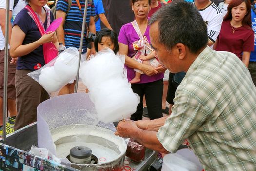 KAOHSIUNG, TAIWAN -- JUNE 20, 2015: An outdoor vendor prepares cotton candy during the 2015 Dragon Boat Festival activities.
