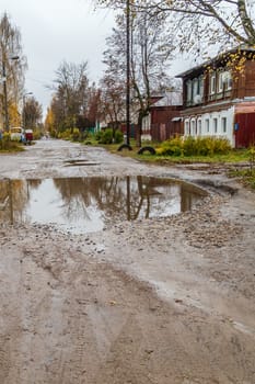 roadway in a provincial Russian city in poor condition, pits and dirt, vertical frame