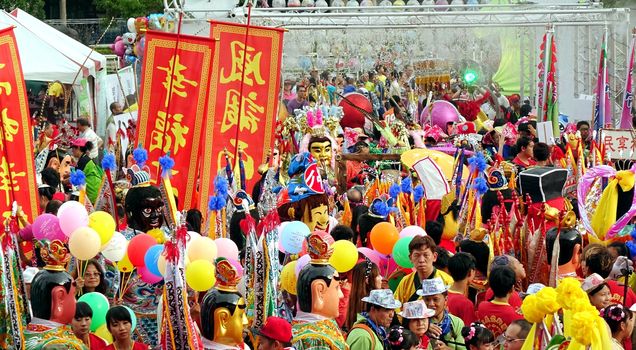 KAOHSIUNG, TAIWAN -- AUGUST 15, 2015: A colorful crowd with balloons and masked dancers packs the area outside the Sanfeng Temple during the Third Prince Carnival.