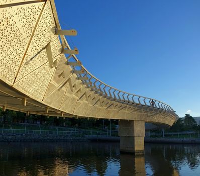 KAOHSIUNG, TAIWAN -- MAY 17, 2014: A modern curved pedestrian bridge at the Heart of Kaohsiung Park illuminated by the afternoon sun.