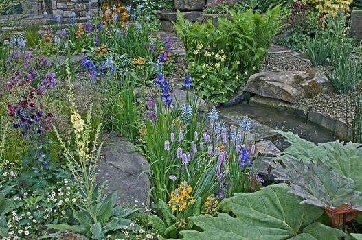 A country cottage and garden situated in a wooded rockery with a colourful display of flowers