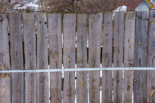 fence around the garden of planks fastened with nails and a metal strip