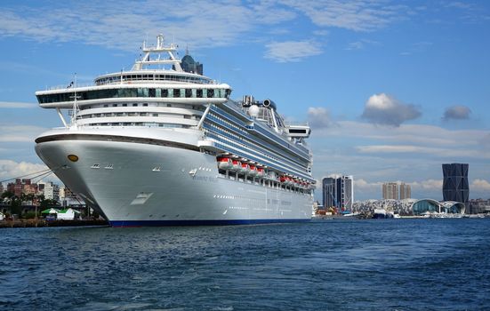 KAOHSIUNG, TAIWAN -- MAY 11, 2014:  The gem class cruise ship Diamond Princess docks at Kaohsiung Port. In the back you can see the new exhibition center and the trade tower.