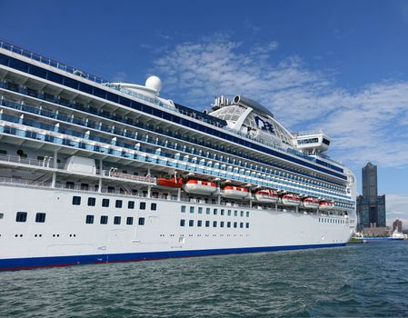 KAOHSIUNG, TAIWAN -- MAY 11, 2014:  The gem class cruise ship Diamond Princess with more than 2000 passengers on board docks at Kaohsiung Port. In the back you can see the 85 story Tuntex Tower.