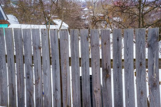 fence around the garden of unpainted boards on a winter day