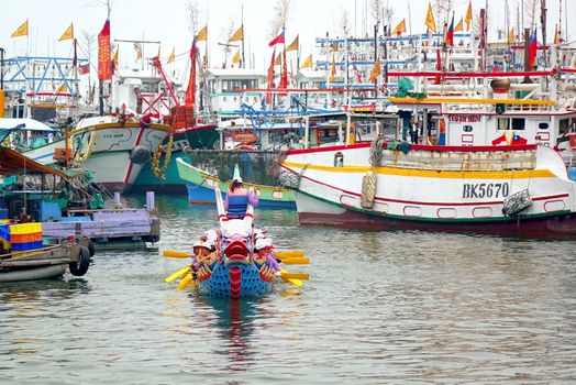 LINYUAN, TAIWAN -- MAY 28, 2017: A dragon boat team has just finished its race. In the back are fishing vessels anchored in the Zhongyun Fishing Port.
