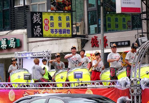 KAOHSIUNG, TAIWAN -- JULY 9, 2016: A percussion ensemble plays large ceremonial drums on the back of a truck during a traditional temple procession.