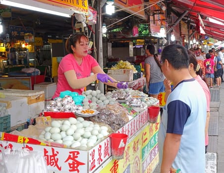 PINGTUNG, TAIWAN -- JULY 6 , 2017: A market vendor offers samples of salted duck eggs, a local specialty, to prospective customers.