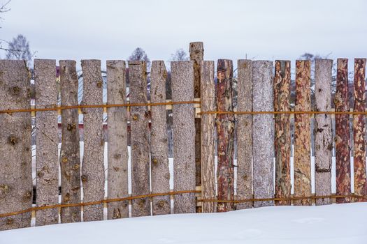 wooden fence of boards nailed to the crossbar on a winter day