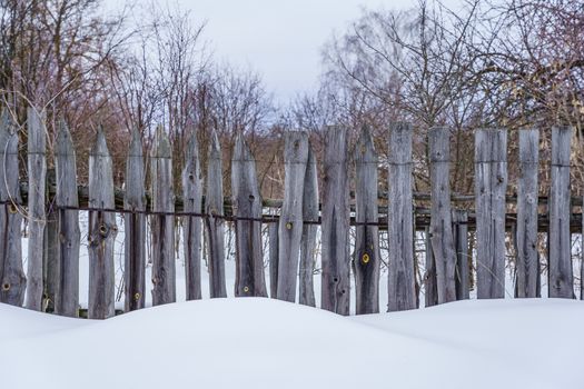 wooden fence of boards nailed to the crossbar on a winter day